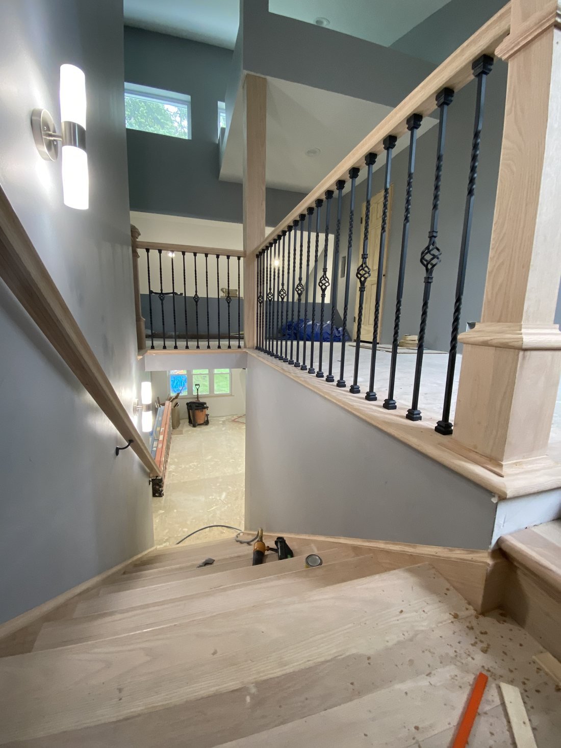 Custom oak stair, handrail and iron baluster railing looking down a two-story stairwell